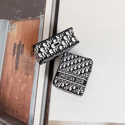 Elegant Dior Premier Chic AirPods Case next to a pair of AirPods and a Dior gift box